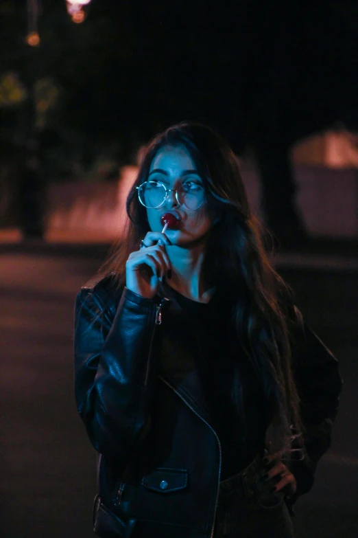 a woman with long dark hair and blue makeup smoking a cigarette