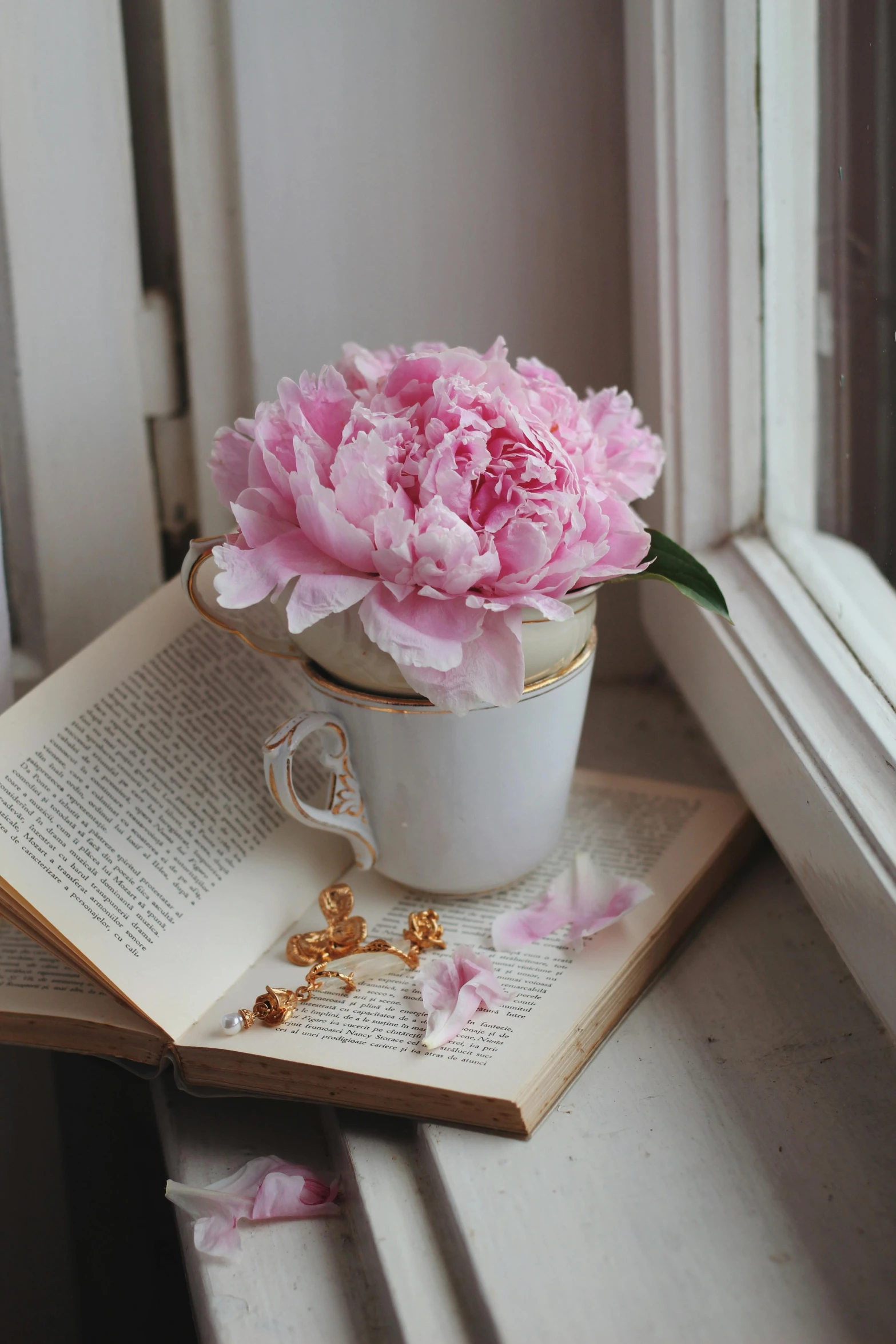 a book and a white cup with pink flowers