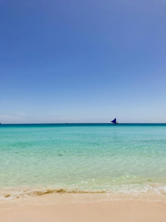 a beach with an ocean view and sailing ship