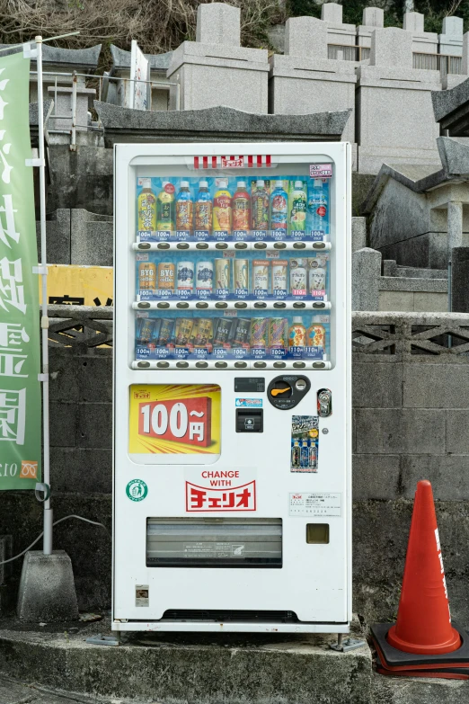 an orange cone and a soda machine in front of a wall with asian writing