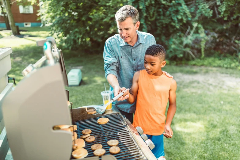 a man helps young children to eat food from the grill