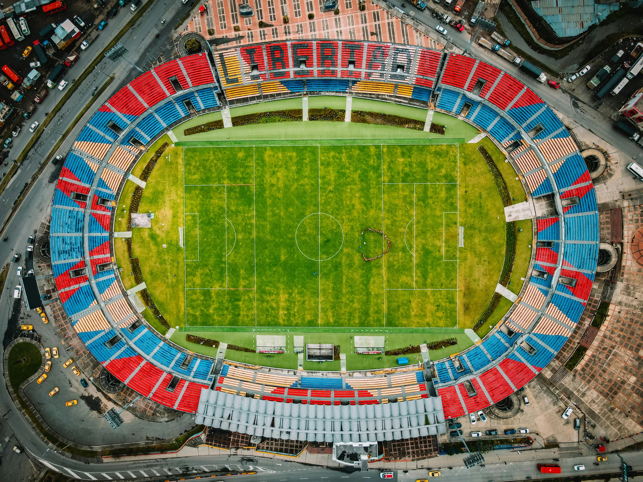 an aerial view of a soccer field that's surrounded by red, blue and yellow chairs