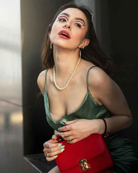 woman with open eyes and red handbag sitting next to a building