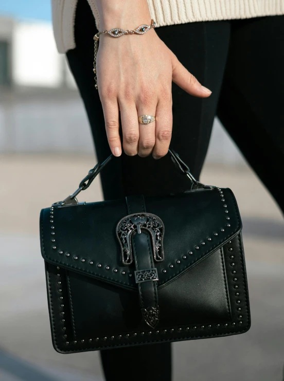 a hand holding onto the handle of a black purse