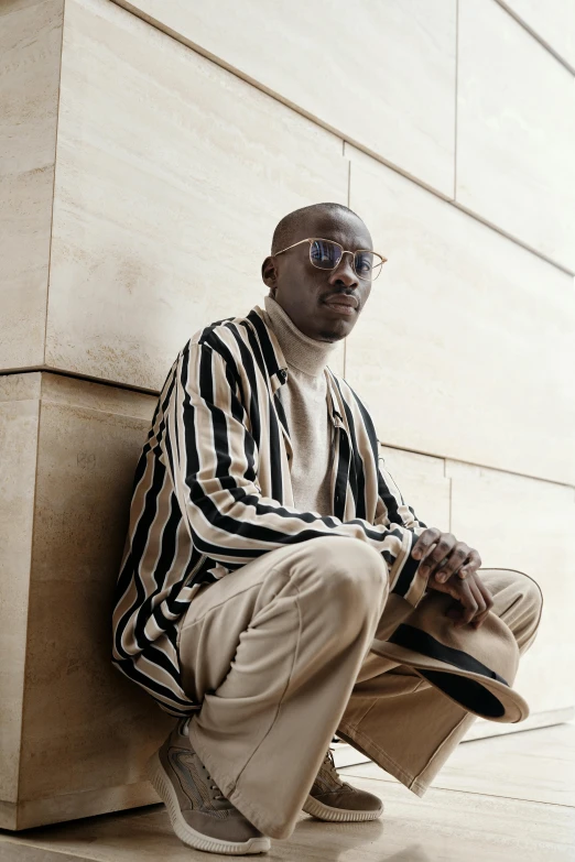 a man sitting against the side of a building on his knees