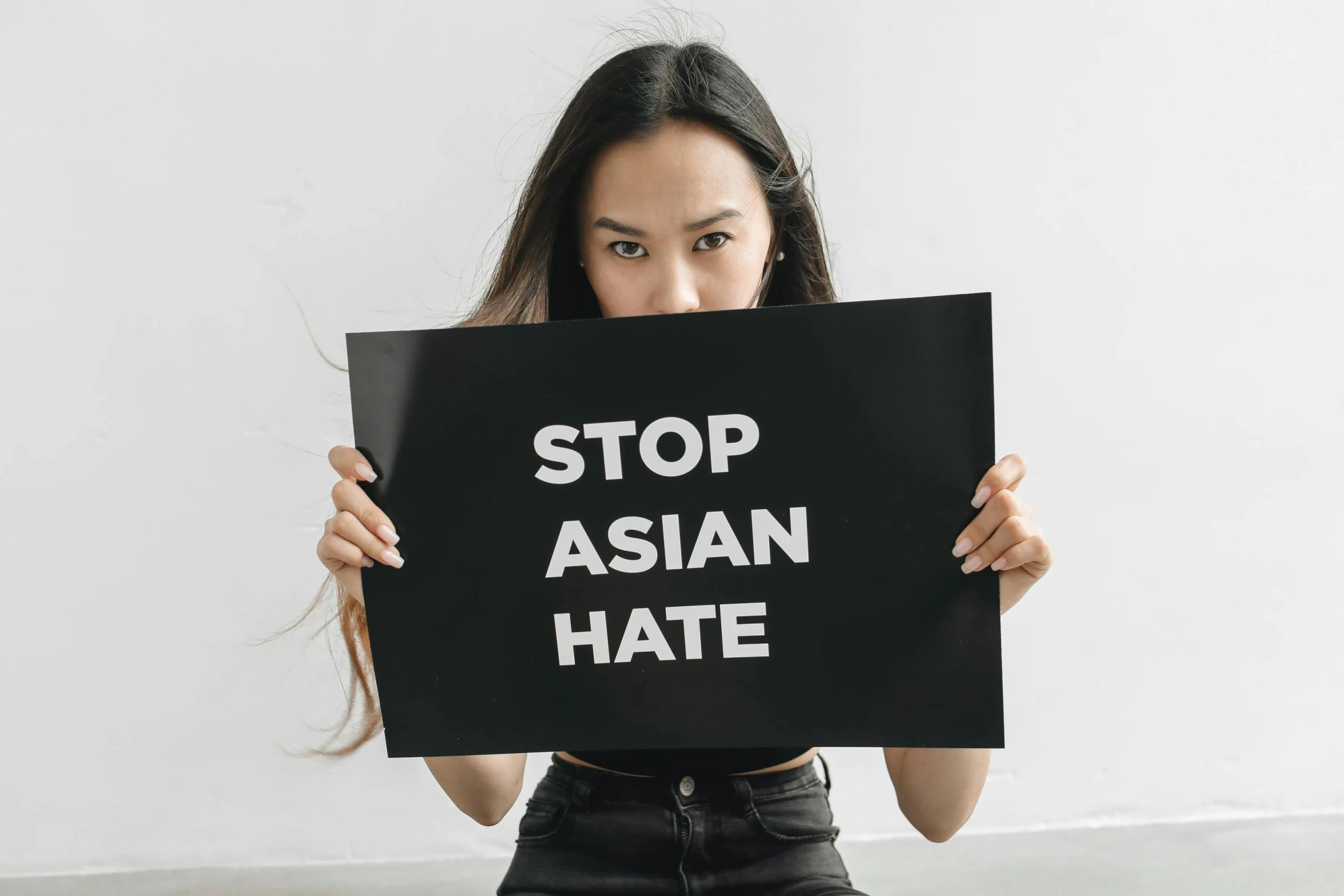 a woman holding up a sign that says stop asian hate