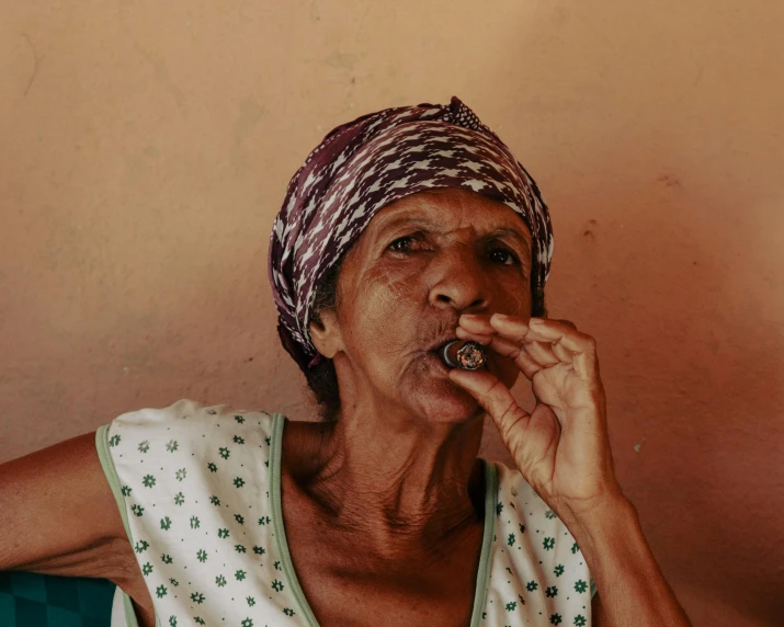 an elderly woman wearing a head scarf is smoking