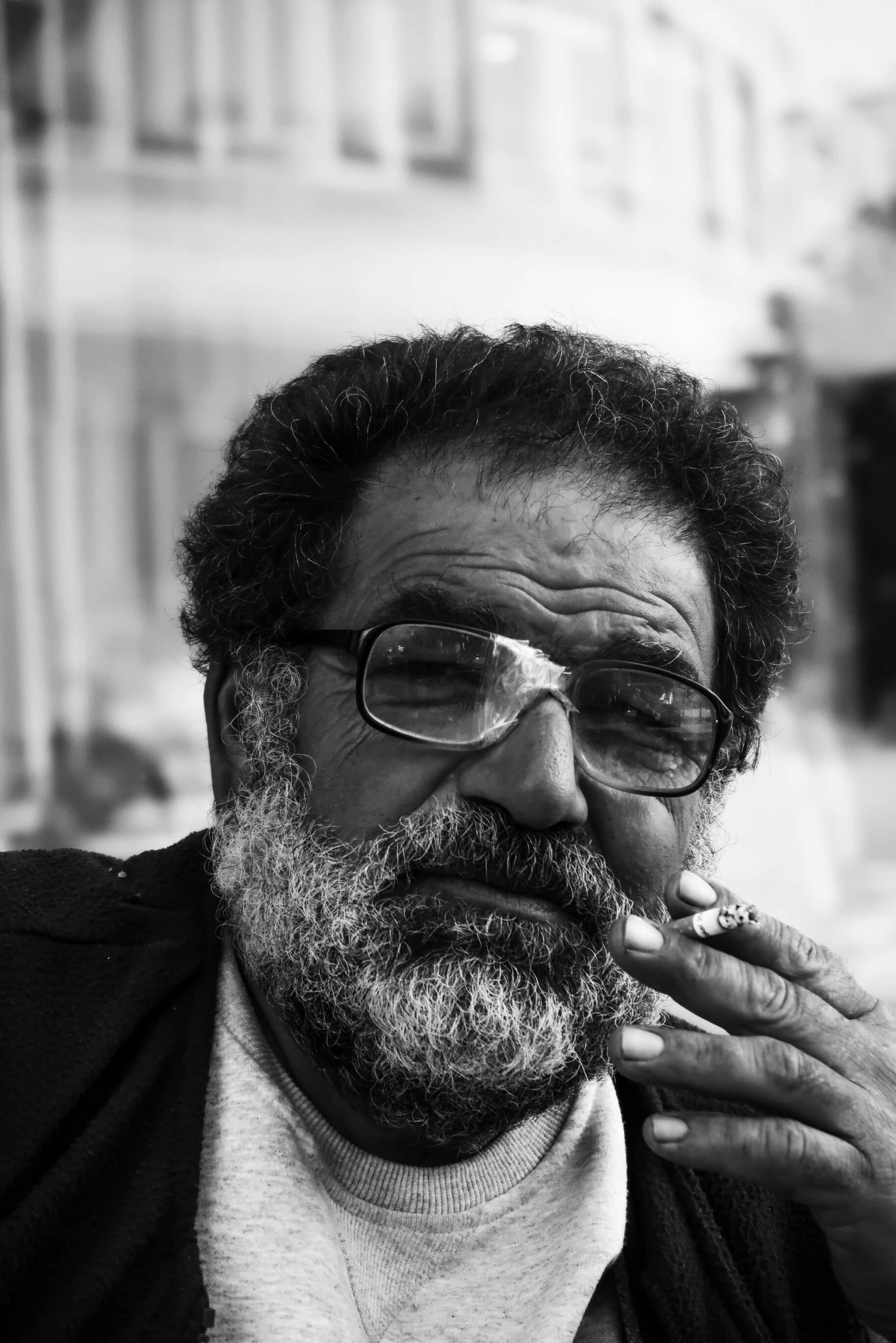 a bearded man smoking a cigarette on a street corner