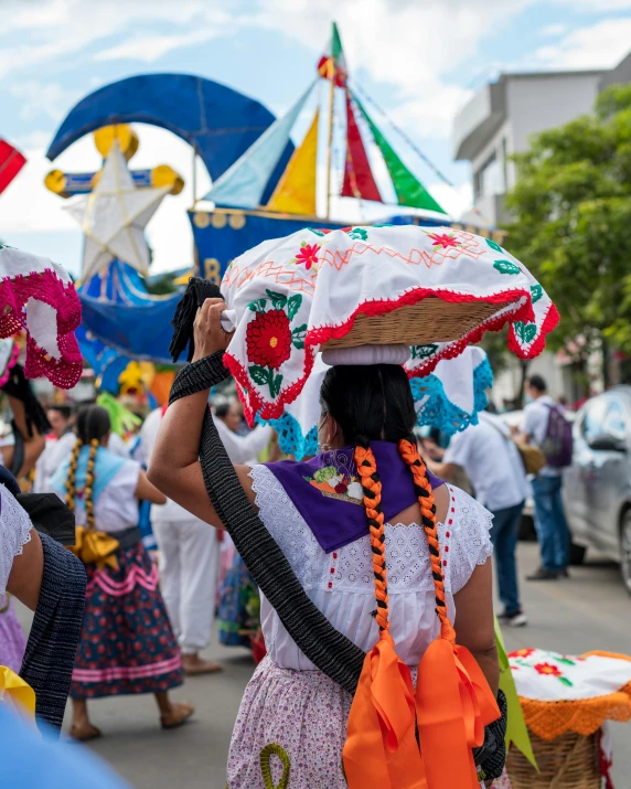 people in the street and in the background carrying decorative decorations on their heads