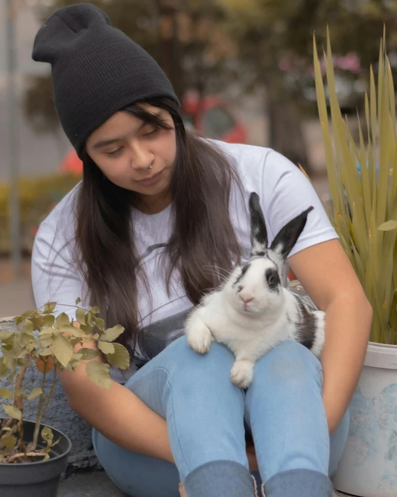 a woman holding a rabbit while sitting on the ground