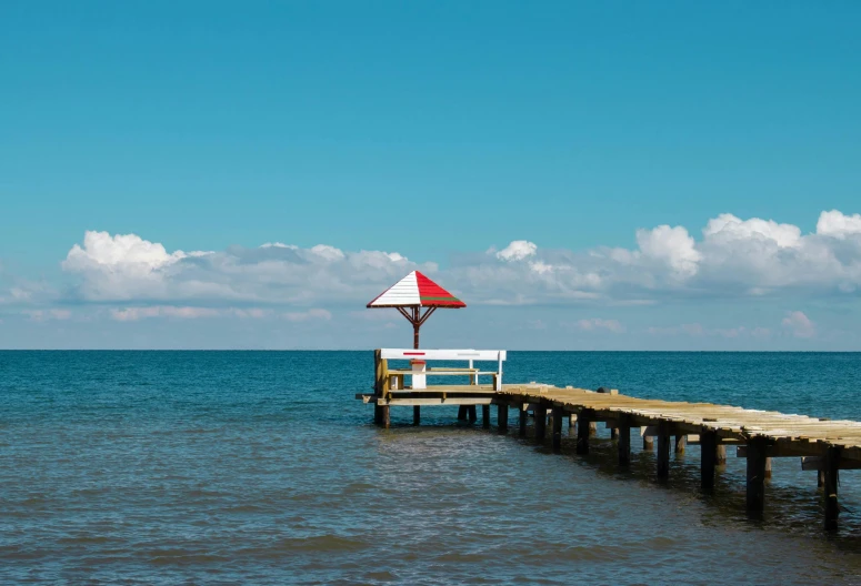 a large red and white umbrella sitting on a pier