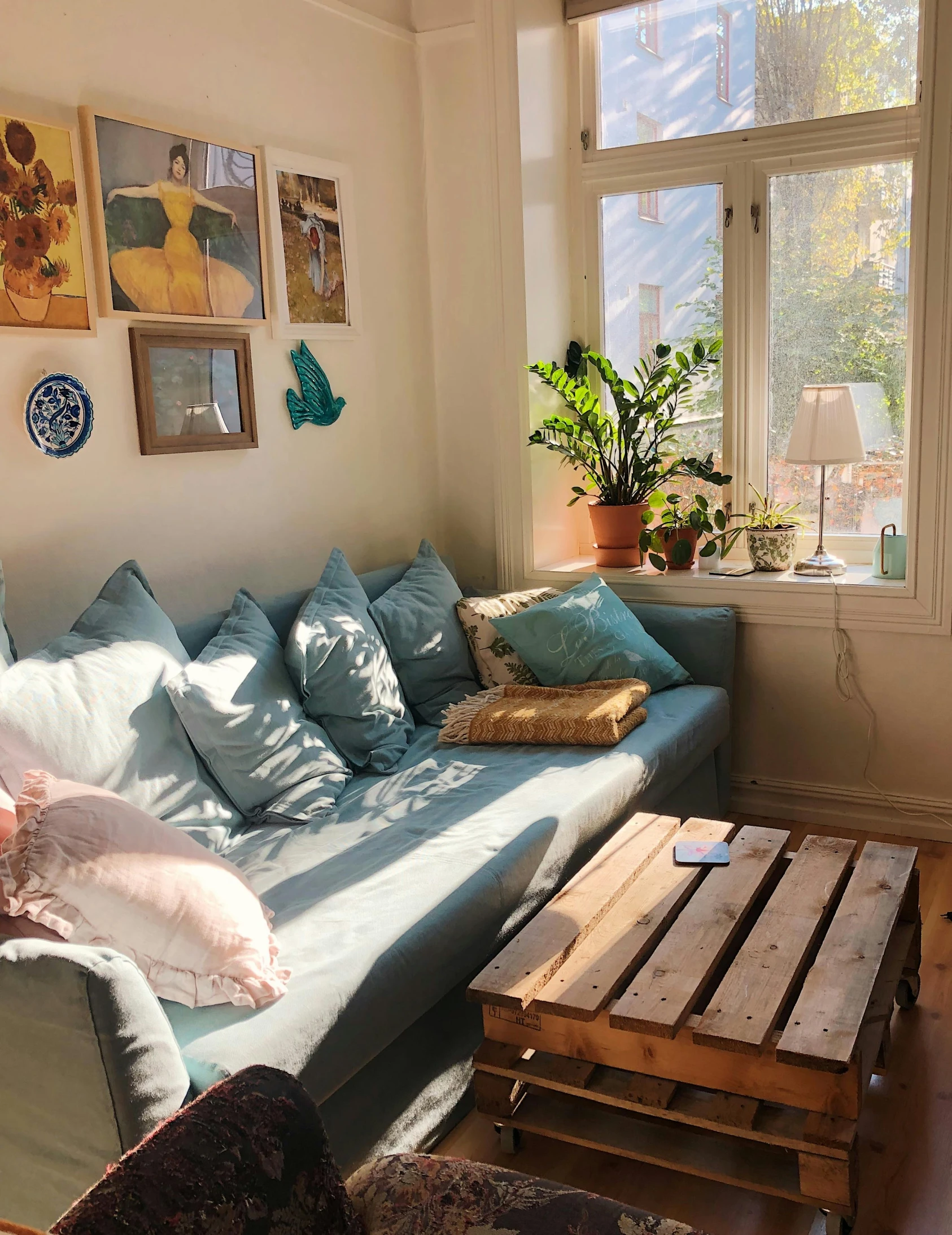 a living room with a blue couch and wooden tables in front of a window