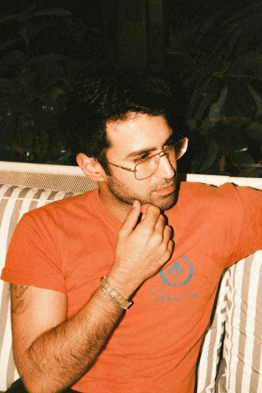 a man in an orange shirt and glasses is sitting