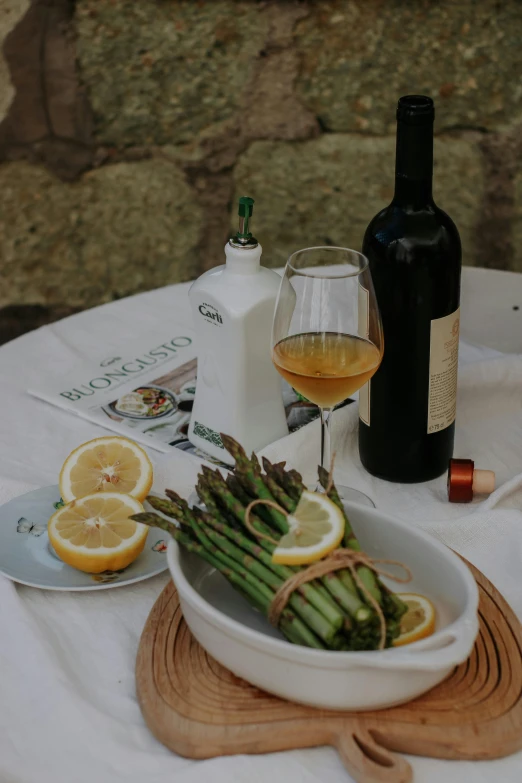 the plate of asparagus and wine is next to a bottle