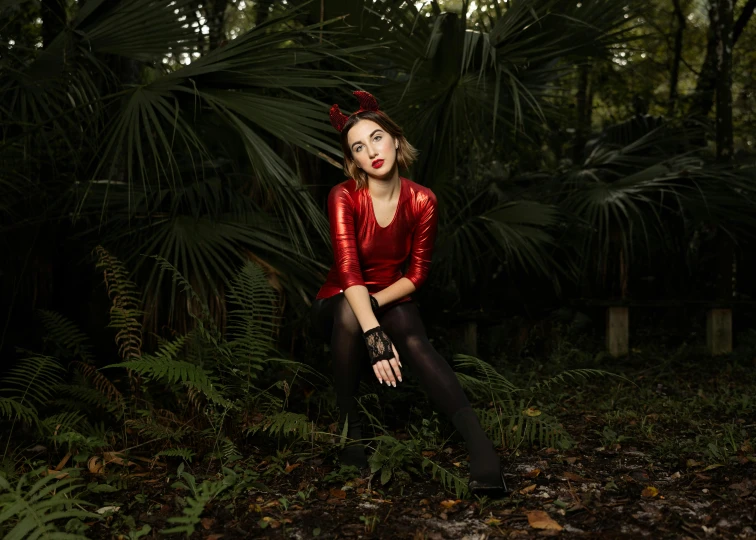 woman in a red jacket sitting down in the forest