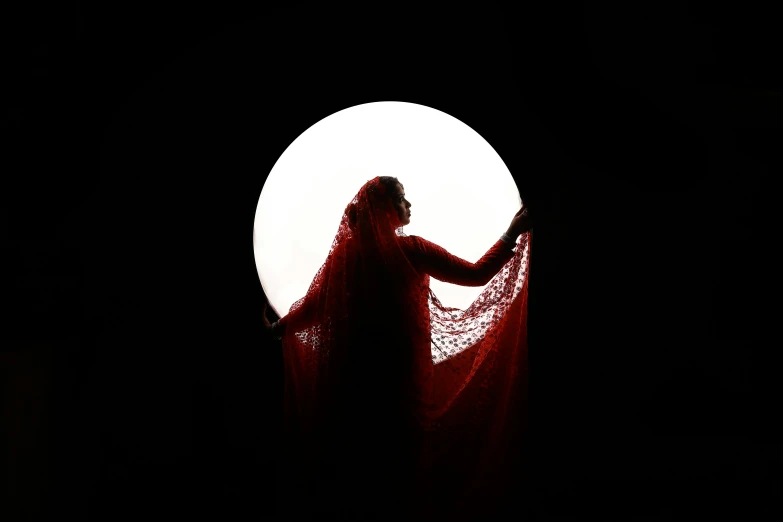 the person with a veil is in front of the full moon