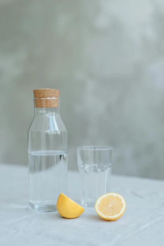 two glasses and a bottle with a half a lemon beside it