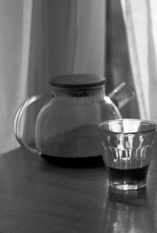 an empty glass on a table with a kettle