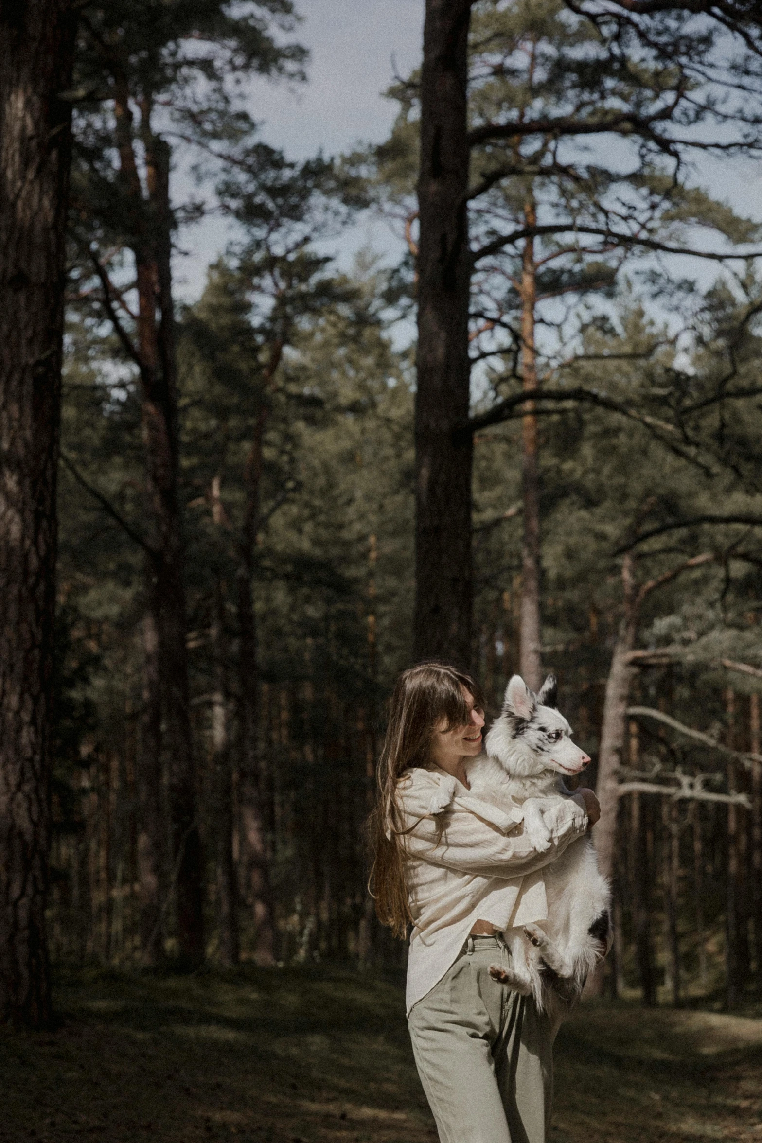 woman carrying a dog walking in a forest