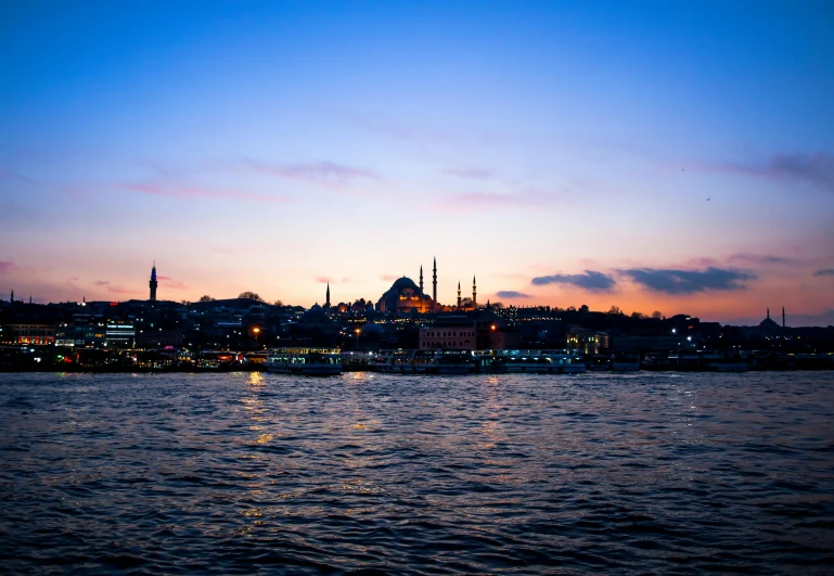 the skyline is shown with boats on it at dusk