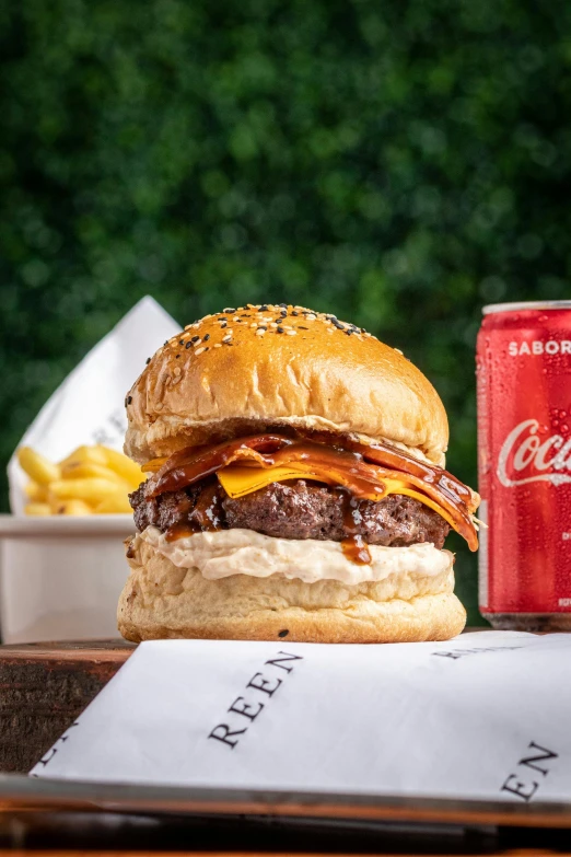 a hamburger and soda sit on a table outside