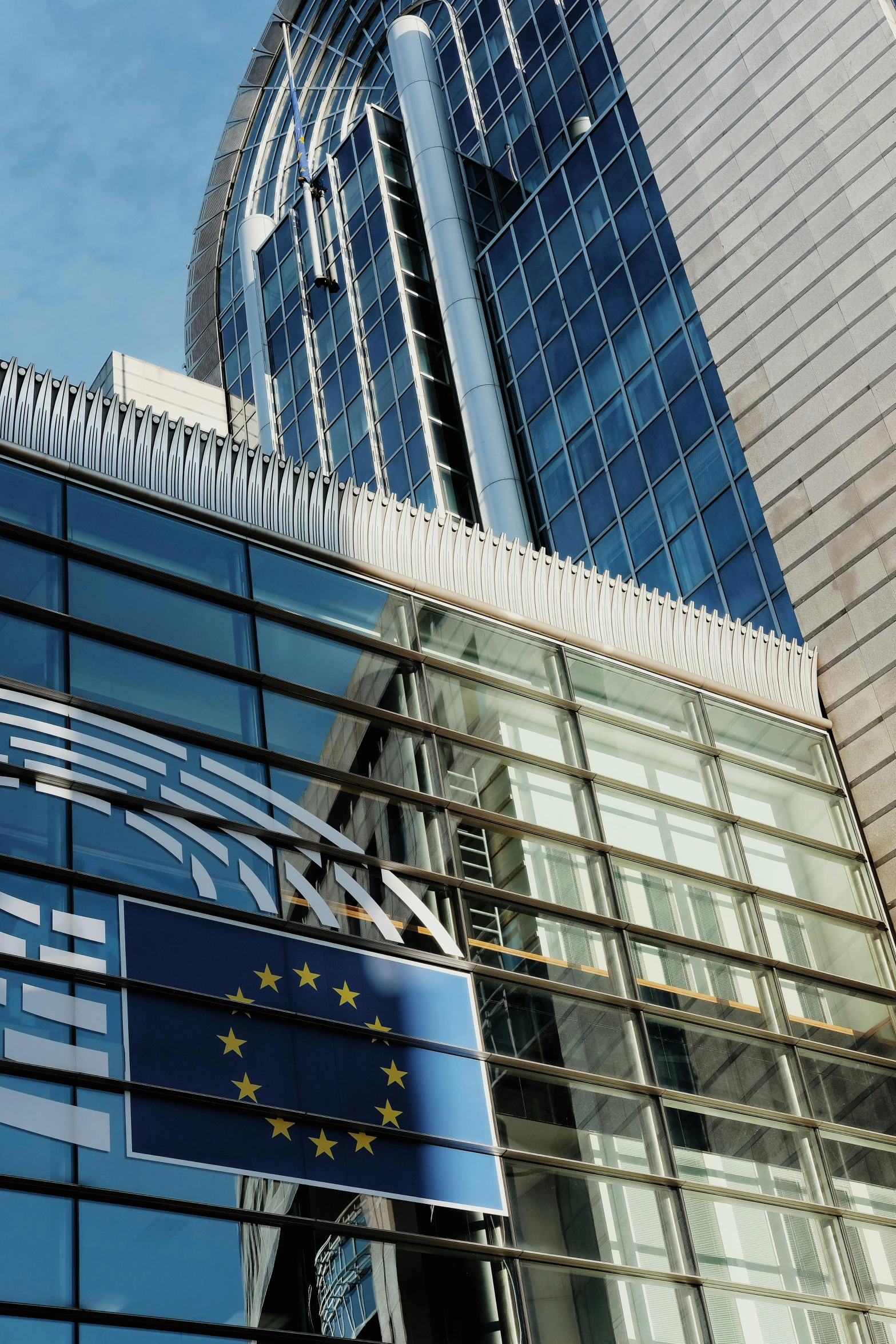 a large glass building with two blue and white buildings in the background