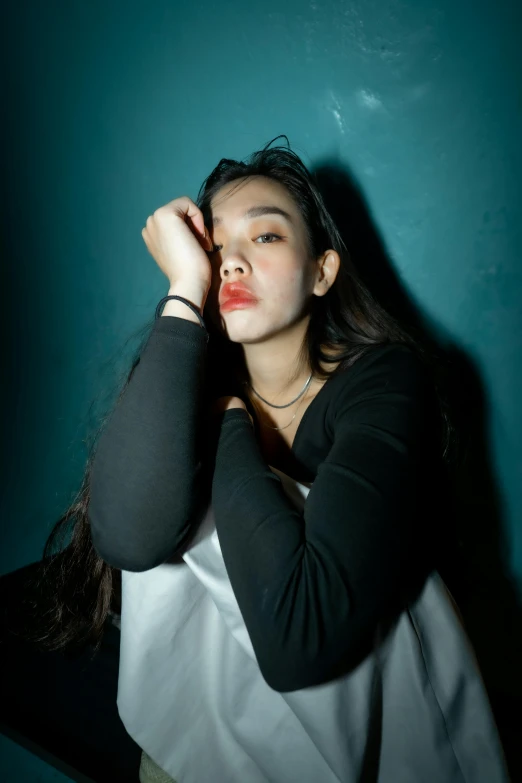 a young woman is sitting down against a wall