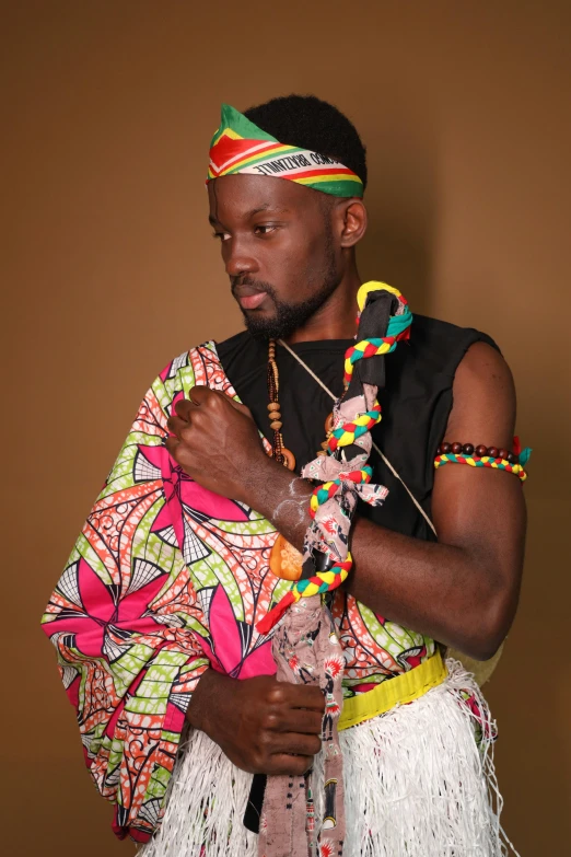 an african man wearing a head dress holding a colorful object