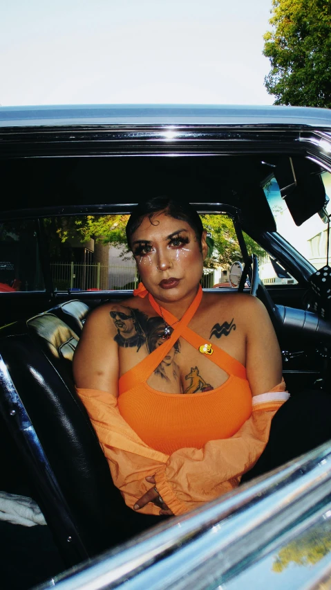 a woman with tattoos sitting in an old car