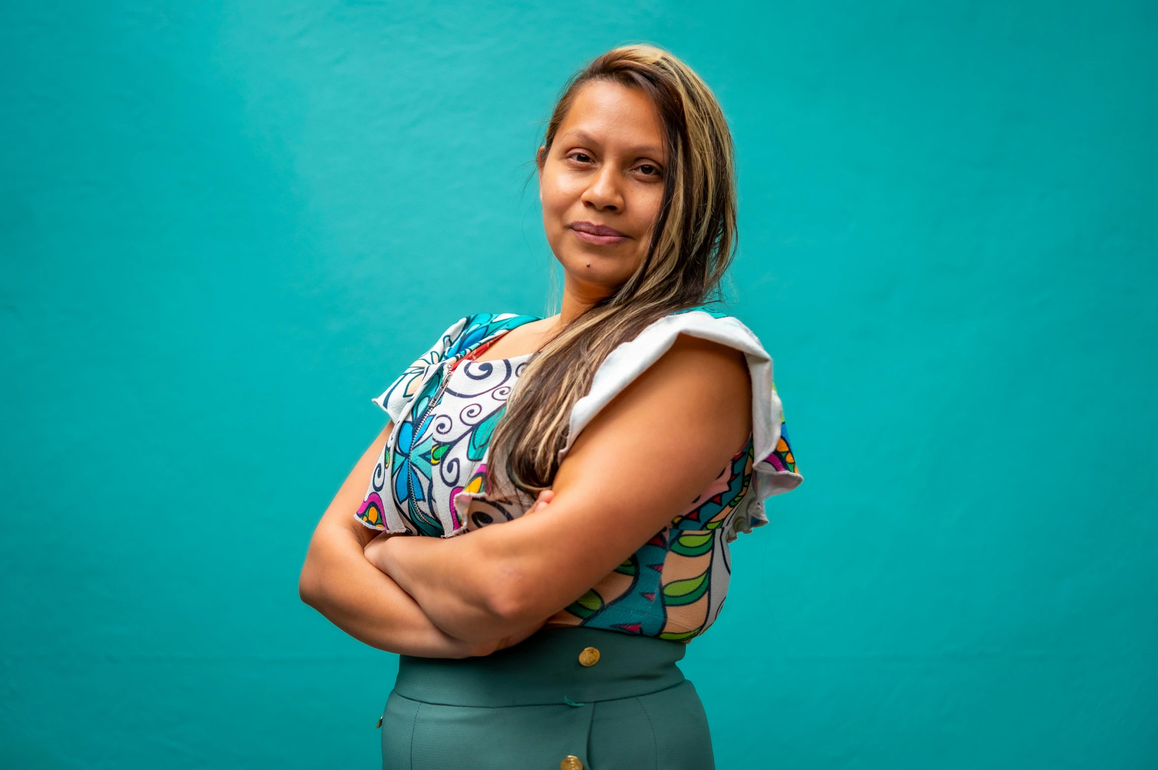 a woman standing with her arms crossed wearing a top and a short skirt