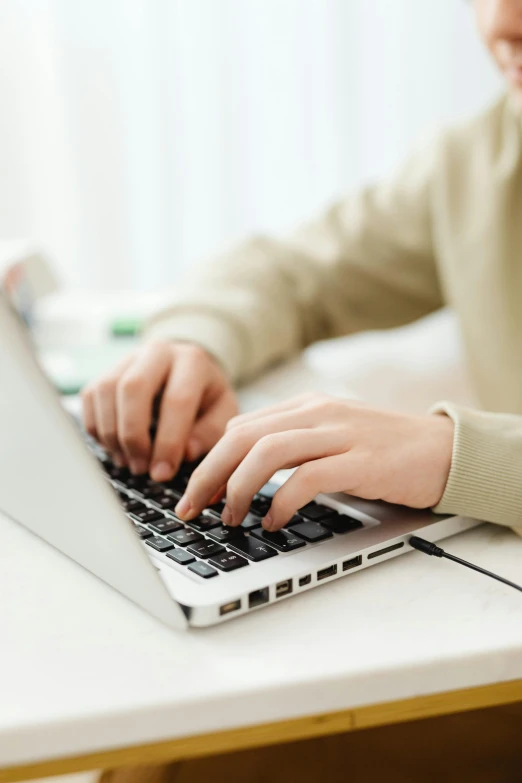 a woman typing on her laptop with a white key