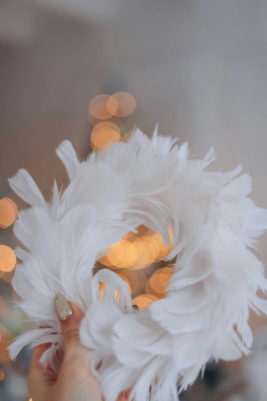 a white feather ball is being held against the camera