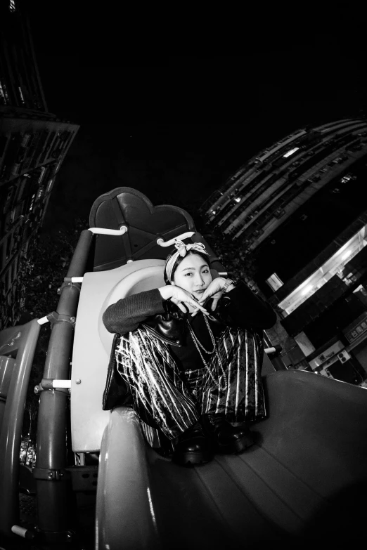 black and white pograph of woman wearing hat, sitting on railing