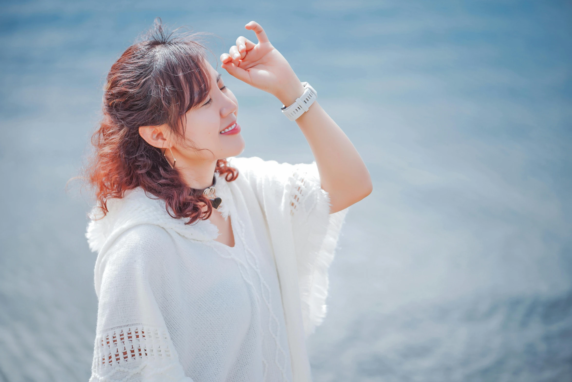 a woman wearing a white robe and looking out into the ocean