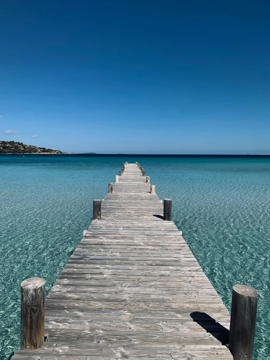 a wooden pier stretching into the water with blue sky