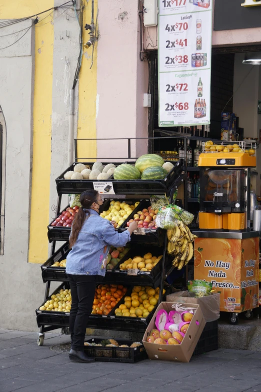 a woman shopping at an outdoor fruit stand