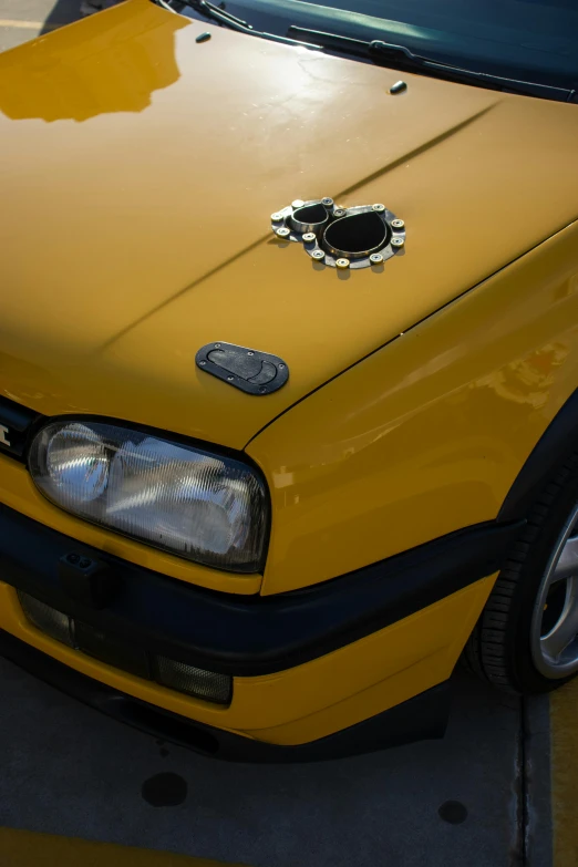 yellow car parked with black hood with mirror grill on top