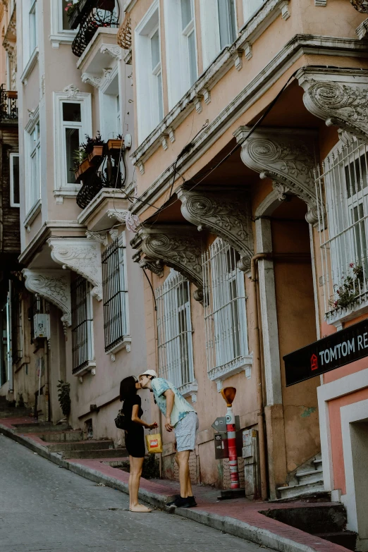 two women are talking on the street near buildings