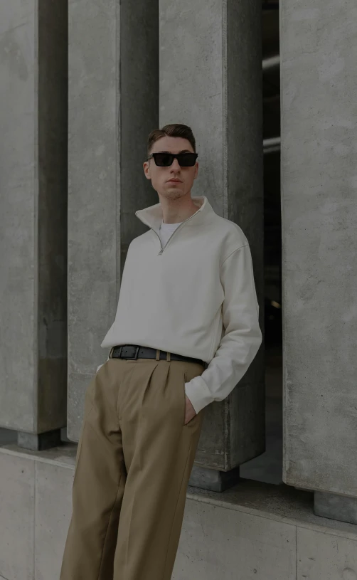 a young man standing in front of a building with a white shirt on