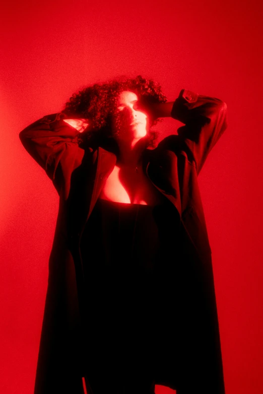 a woman covers her hair while standing against a red background