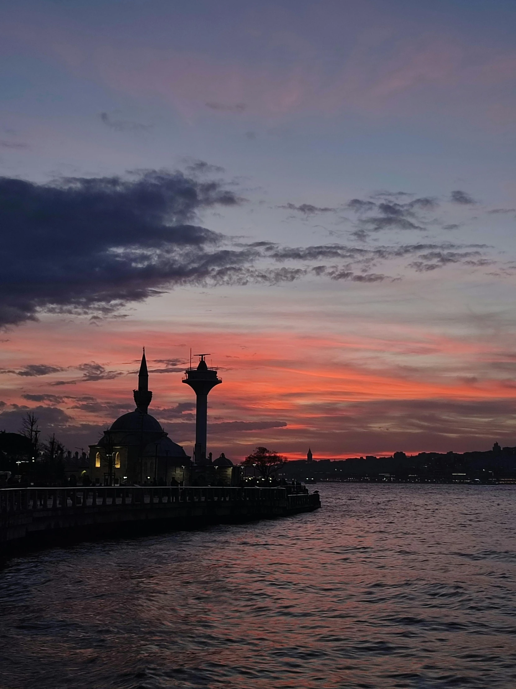 the view from the pier looking over the water with a sunset behind it