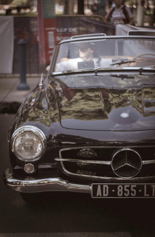 the front end of an antique mercedes sits in traffic