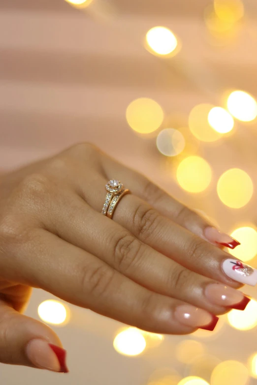 a manicured hand holding a gold diamond ring