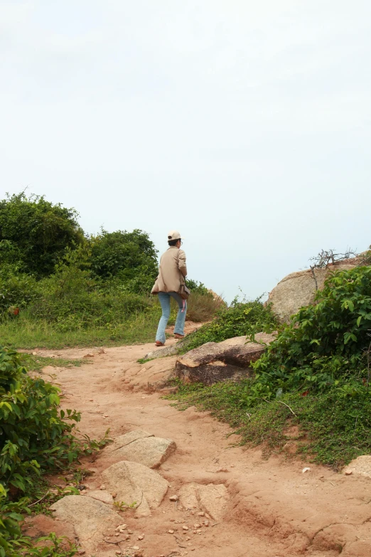 a man in jeans and a hat stands on a trail