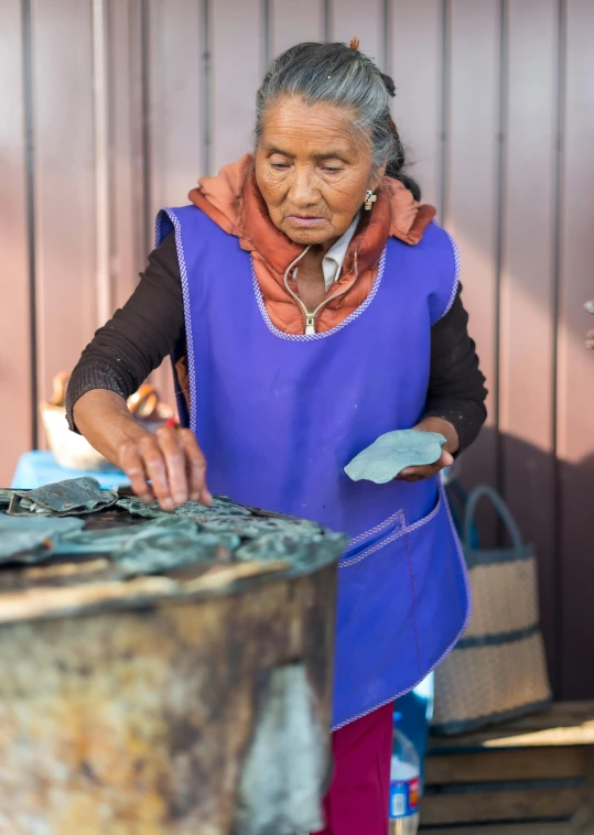 an old woman with a blue vest is looking at soing