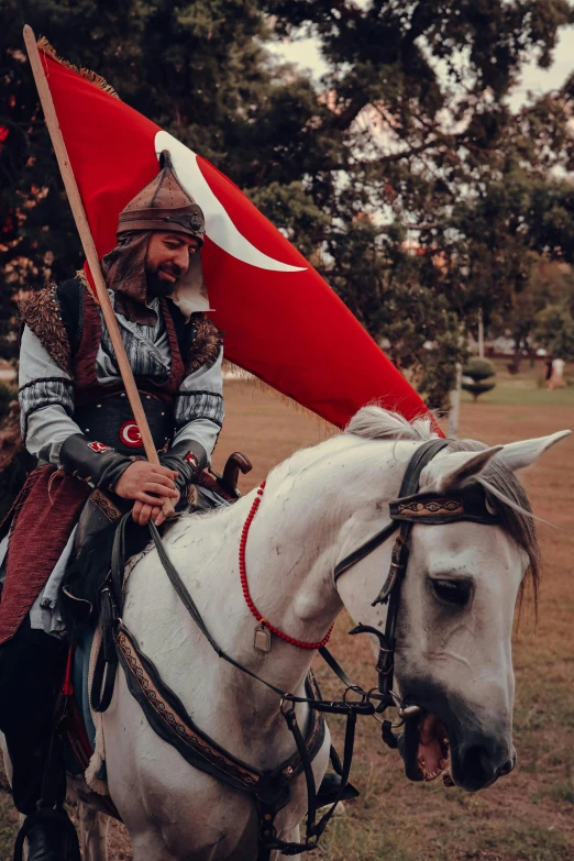 a man dressed in period clothing rides on a horse with a flag