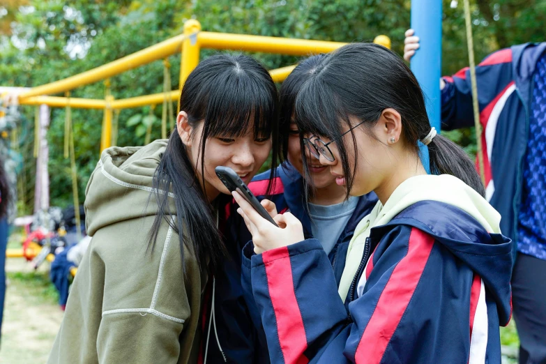 two young women are playing on their cell phones