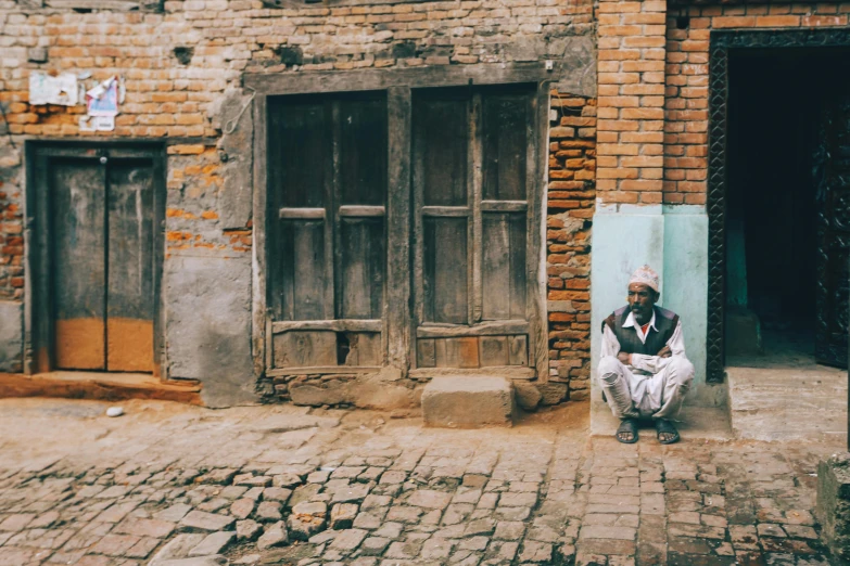 a man sitting on the ground near a building