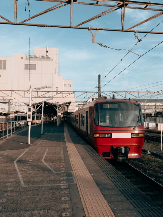 a red passenger train is traveling through a train station