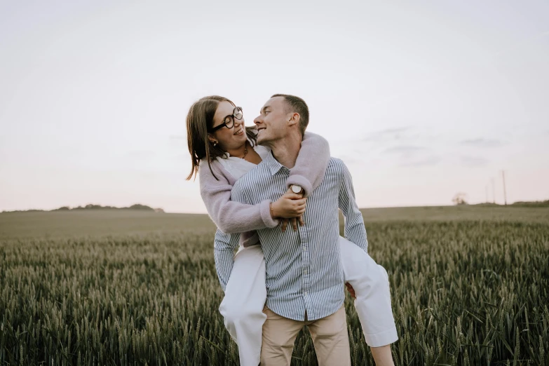 a man carries his girlfriend through a wheat field